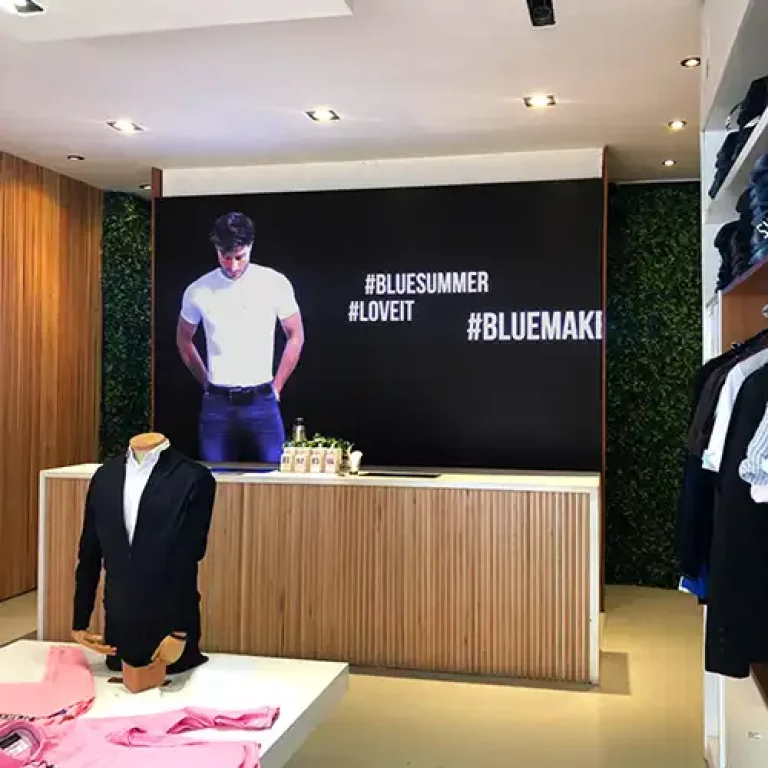 Pantalla Multiled ultradelgada instalada detrás de cajas para hacer promociones en casa de indumentaria Bluemakers en Santa Fé